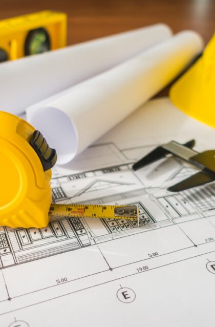 Construction plans with yellow helmet and drawing tools on bluep Construction plans with yellow helmet and drawing tools on blueprints